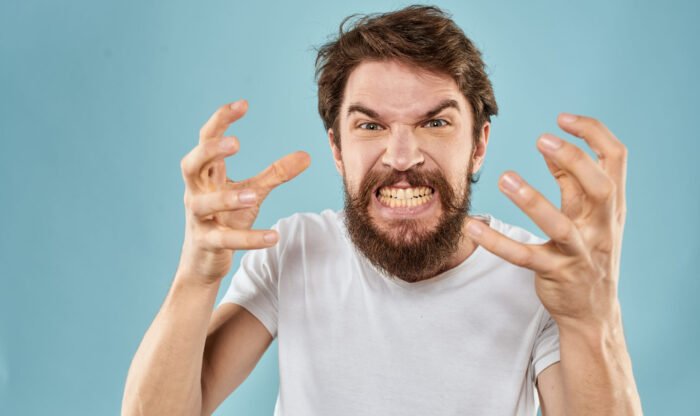 Bearded man in white T-shirt emotions gestures with hands displeased facial expression blue background. High quality photo