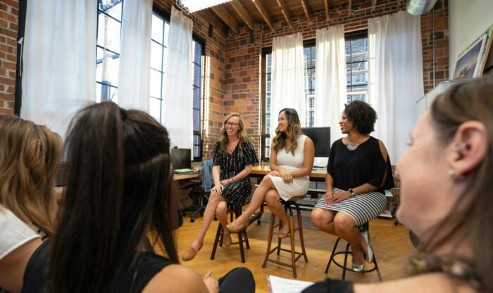 Women engaging in a panel discussion in a modern office setting, fostering an inclusive business community.